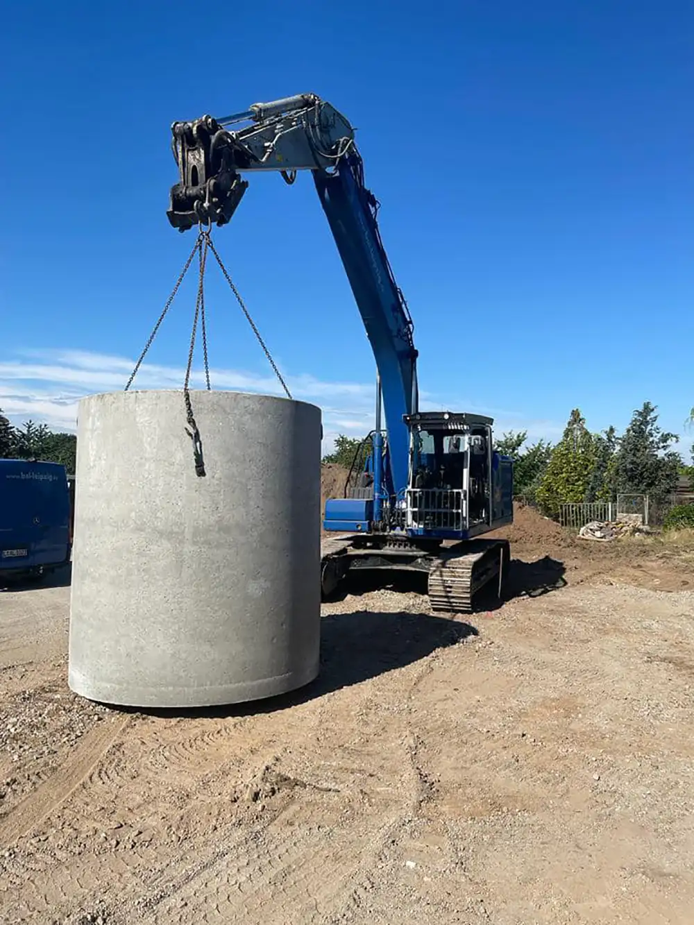Kran hebt einen großen Regenwassertank auf einer Baustelle bei sonnigem Wetter